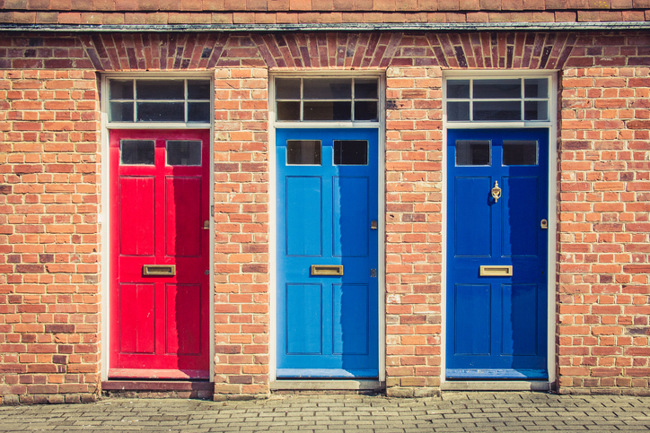 Three differently coloured front doors at the entrance of old English terraced houses. Canterbury, England.