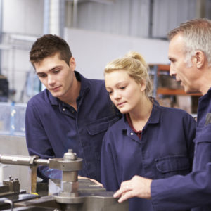 Engineers working in a manufacturing plant with more senior worker training junior workers