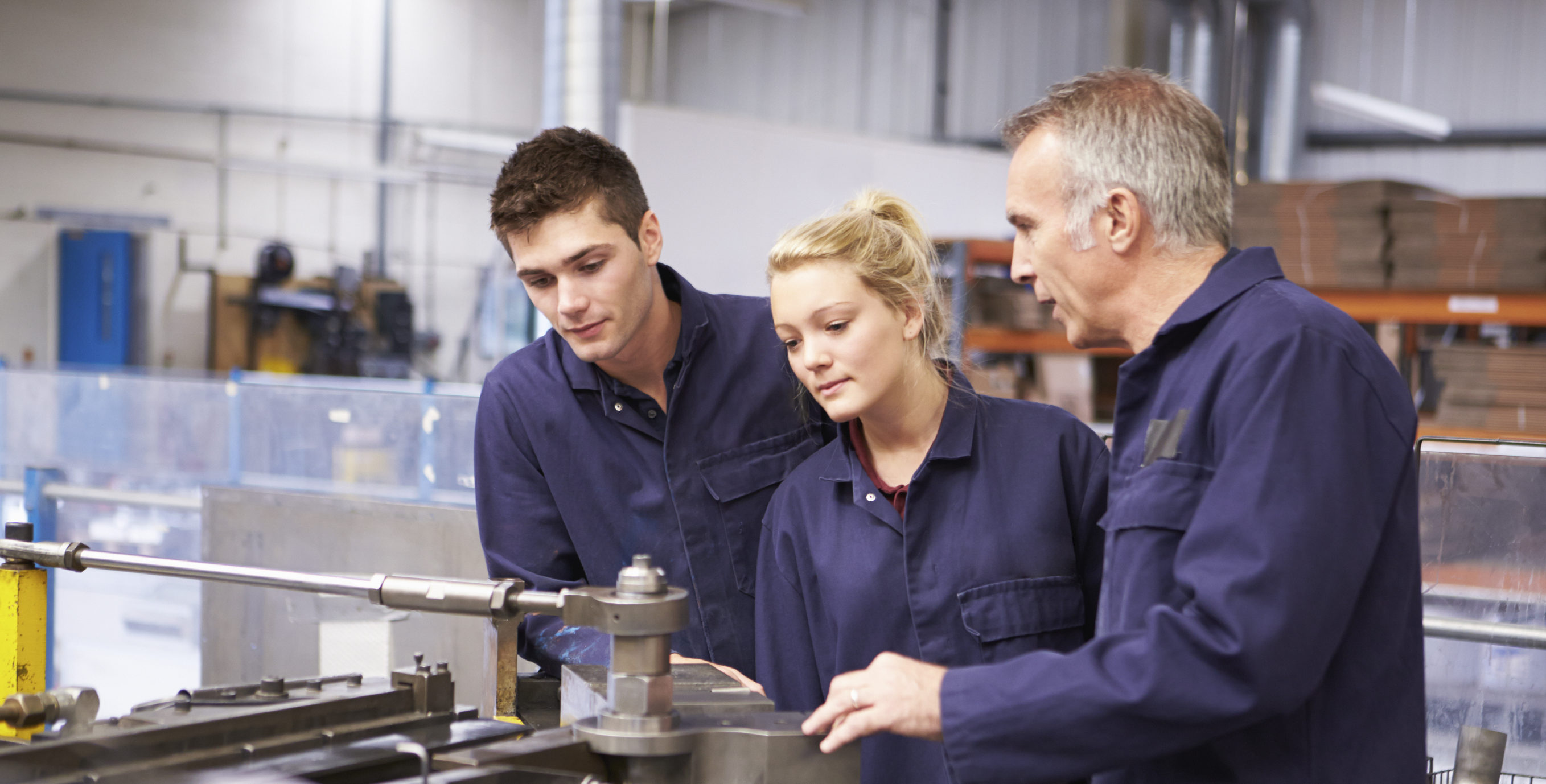 Engineers working in a manufacturing plant with more senior worker training junior workers