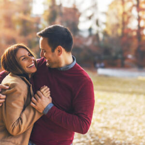 Couple in love hugging and enjoying a public park in autumn