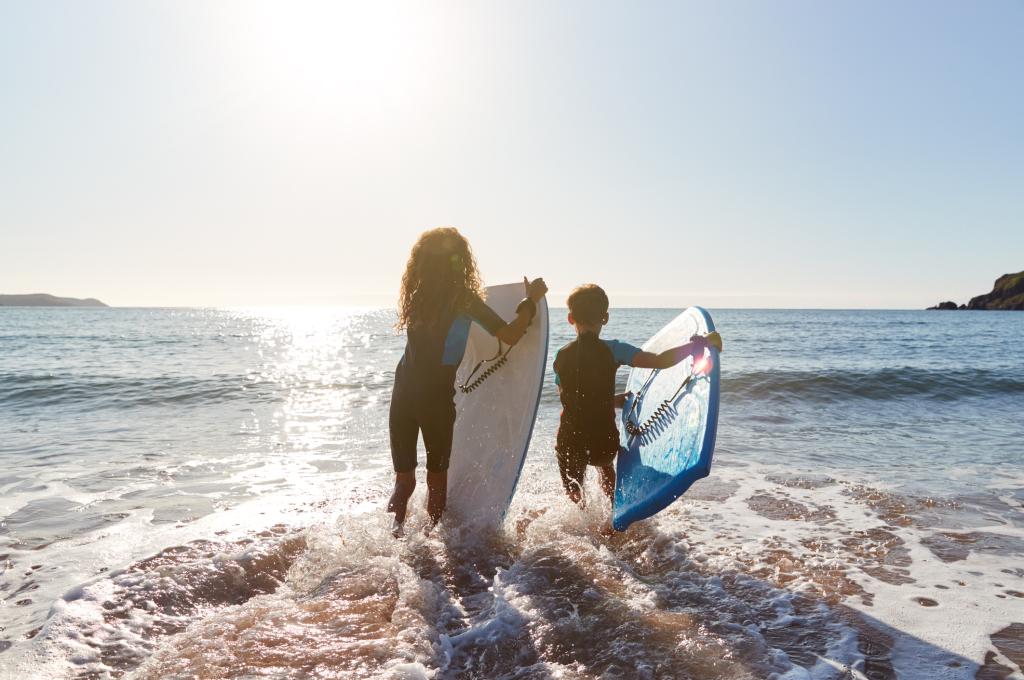 Two children in the ocean with bodyboard attending club activities