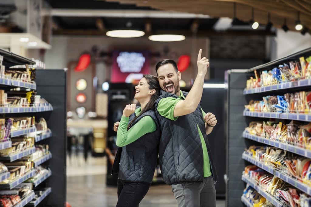 Two happy smiling employees dancing in a supermarket