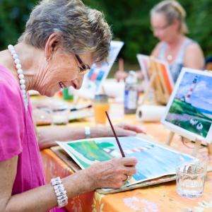 Group of care home residents smiling and painting outdoors.