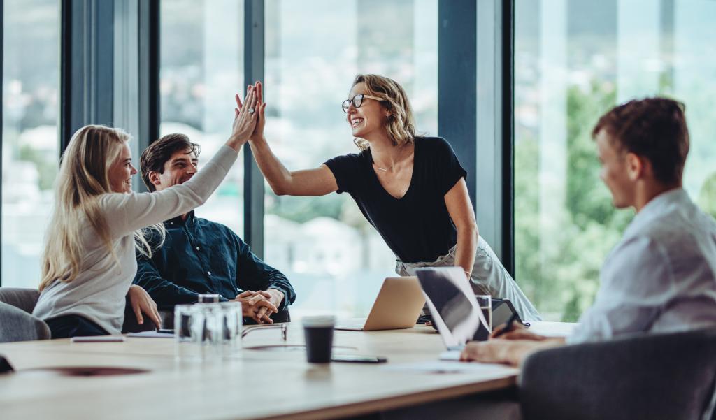 Female professional giving a high five to her colleague in conference room.