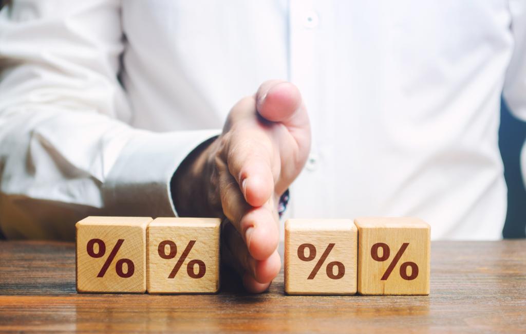 Division of assets visualised by a man putting his hand in the middle of four wooden blocks showing percentage signs.