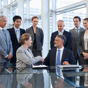 Business people shaking hands in conference room following investment