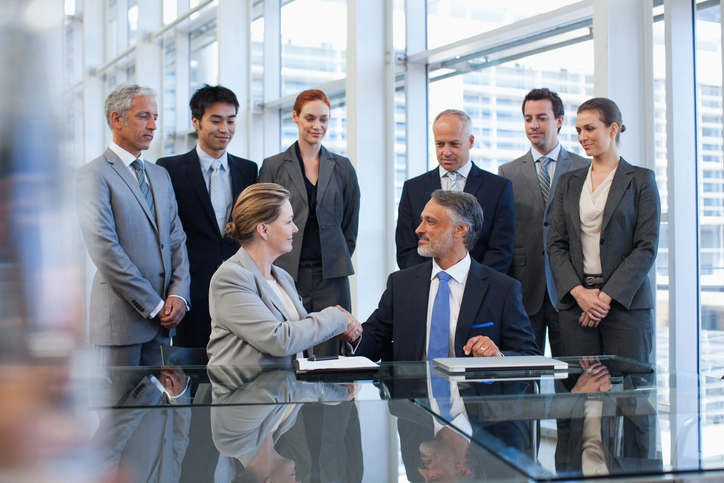 Business people shaking hands in conference room following investment
