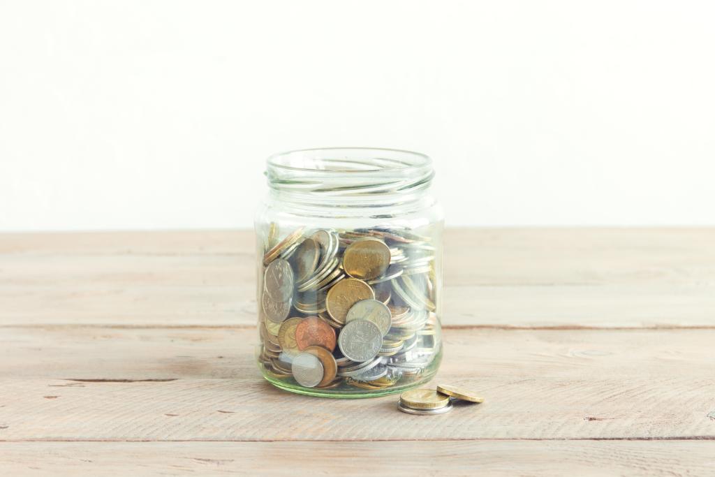 Coins filling up a tip jar on a wooden table