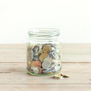 Coins filling up a tip jar on a wooden table