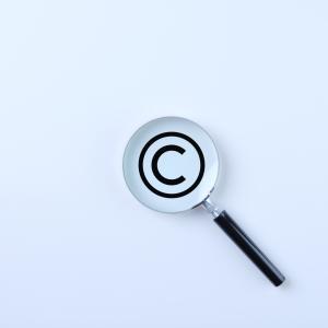 Magnifying glass magnifies the copyright symbol on a white background.