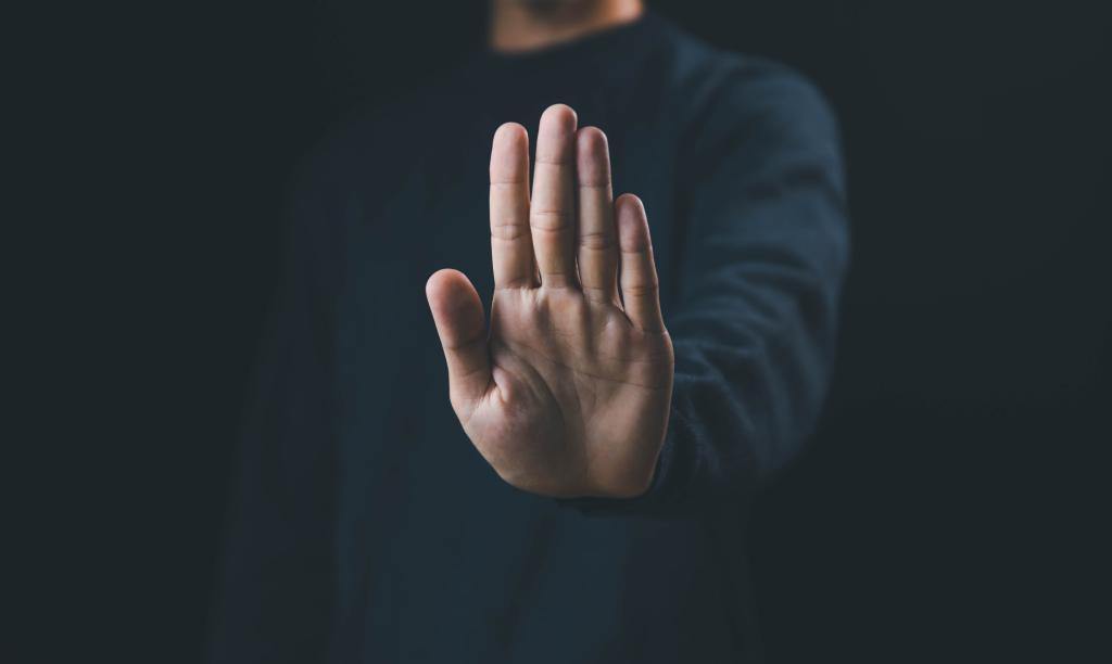 A man holding his hand out with the palm facing forward as a sign to stop. As a concept for anti-bullying week.