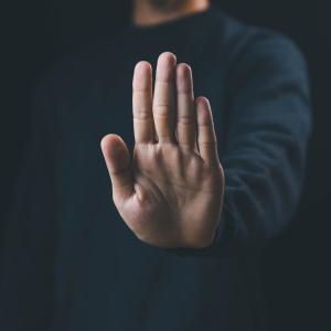 A man holding his hand out with the palm facing forward as a sign to stop. As a concept for anti-bullying week.