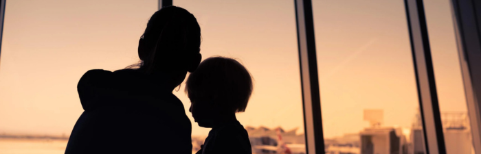 Mother and her little son in silhouette waiting for boarding in the airport.