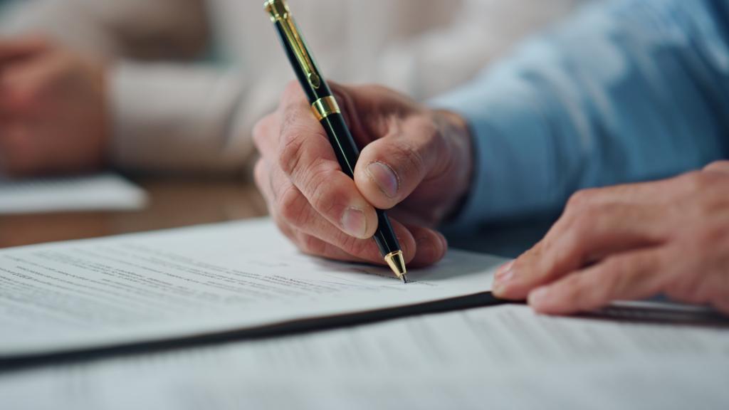 Close up of a hand signing a settlement agreement