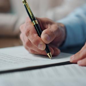 Close up of a hand signing a settlement agreement