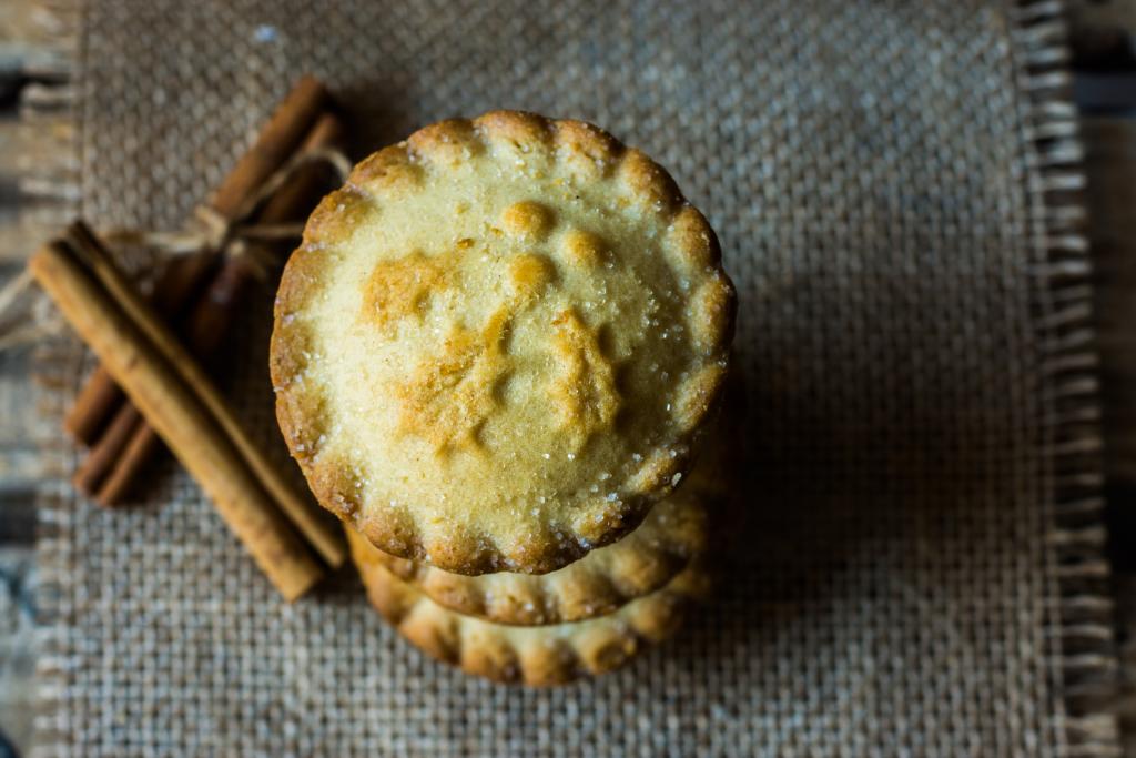 Stack of mince pies on burlap cloth with cinnamon sticks