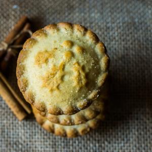 Stack of mince pies on burlap cloth with cinnamon sticks