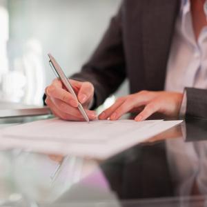 Businesswoman writing on paper at desk