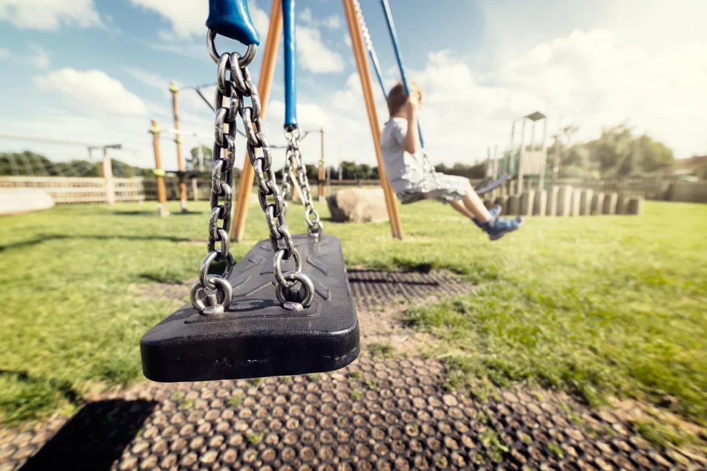 Child swinging on a swing set outside by himself