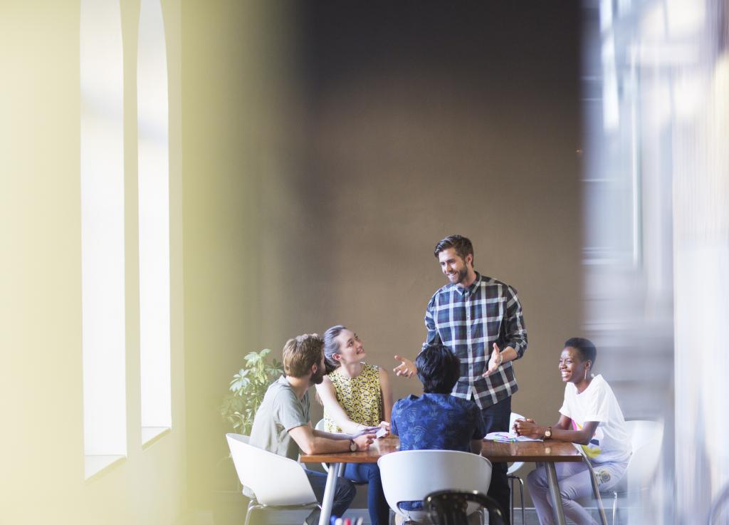 Casual businessman leading meeting at office table