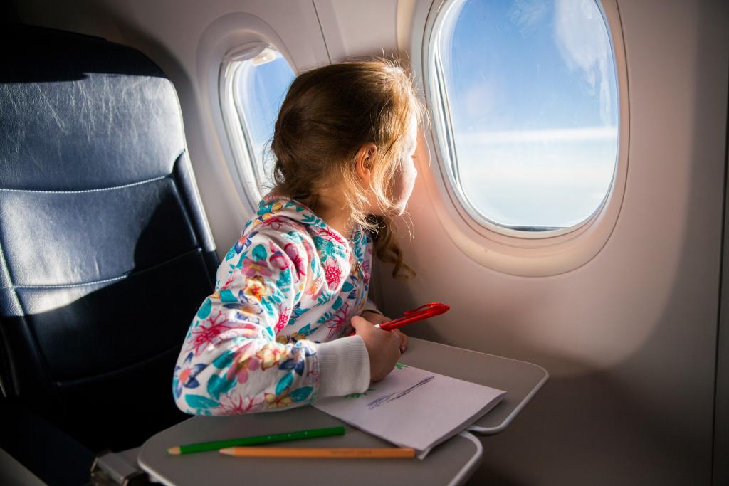 Child drawing picture with crayons in airplane. Concept for - Application for summary return of a child to a non-Hague country