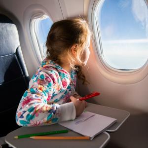 Child drawing picture with crayons in airplane. Concept for - Application for summary return of a child to a non-Hague country