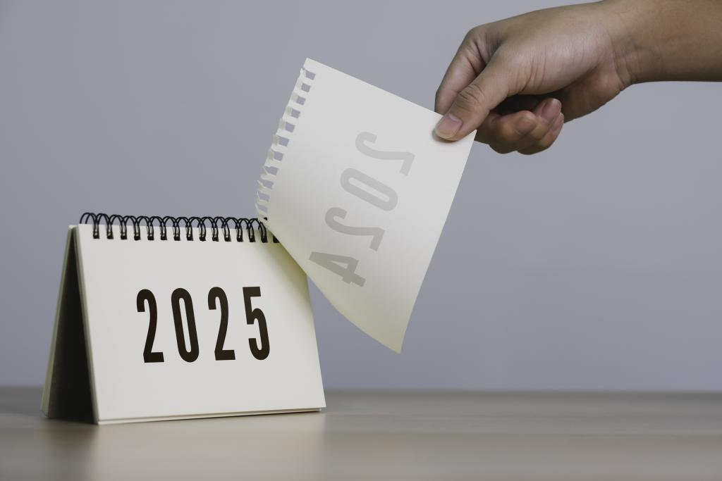 A person's hand is pulling a calendar from 2024 to 2025.