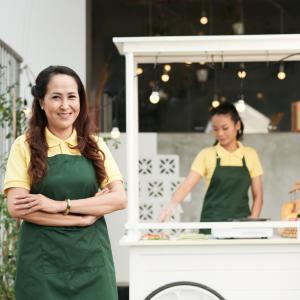 Food cart owner standing and smiling in front of their stand