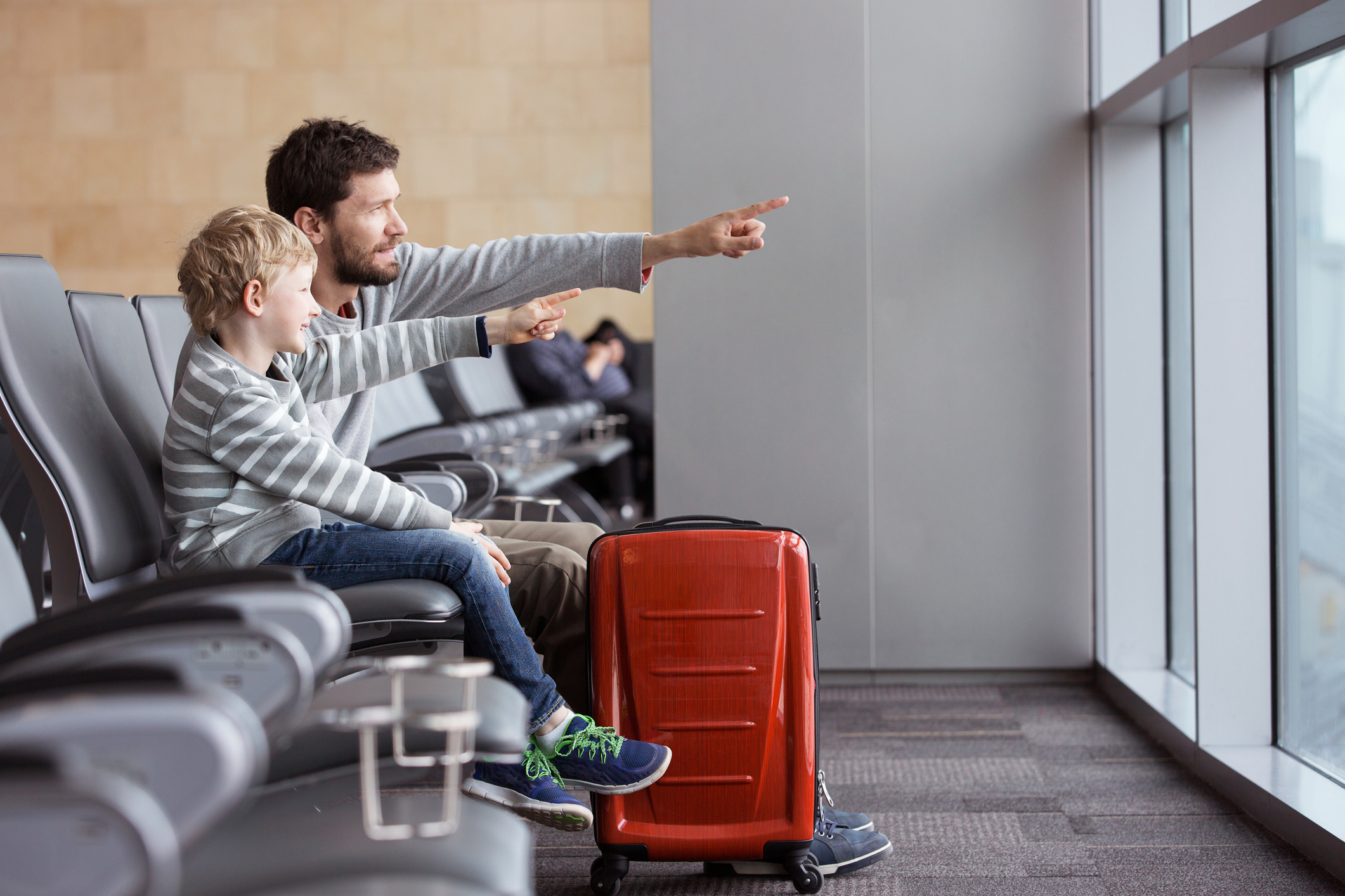 positive smiling boy and his father waiting at the airport for plane.