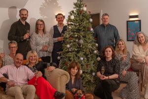 Sleeps 12 team at Christmas sat and stood together around a Christmas tree