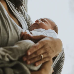 A mother holding a young baby close to her chest