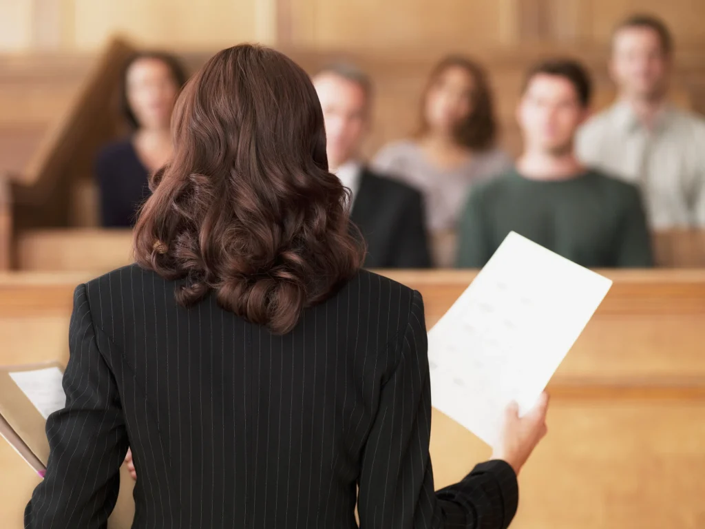 An expert evidence presenting information in a Court room seen from behind holding paperwork