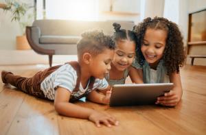 Three siblings watching a tablet together and smiling